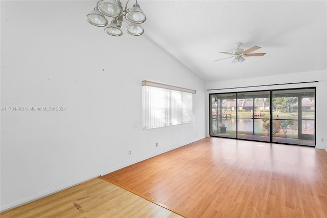 spare room featuring ceiling fan with notable chandelier, hardwood / wood-style flooring, and high vaulted ceiling