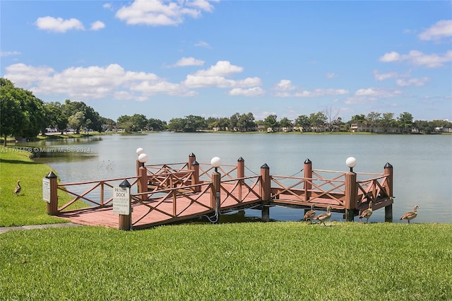 view of dock with a yard and a water view