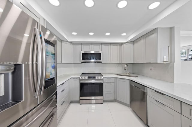 kitchen with sink, stainless steel appliances, light stone counters, gray cabinets, and light tile patterned floors