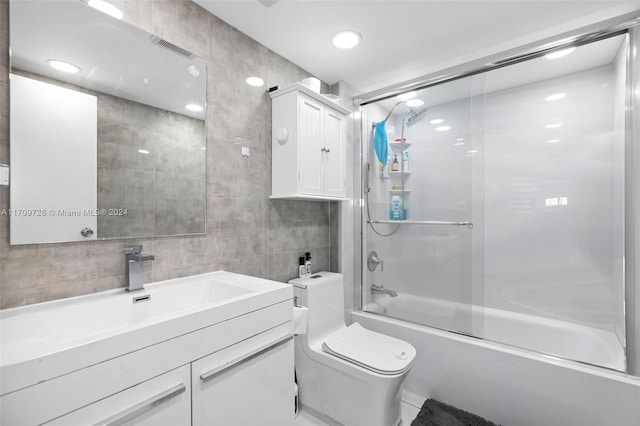 full bathroom featuring vanity, toilet, tile walls, and enclosed tub / shower combo