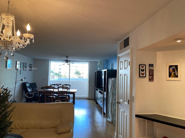 living room with a textured ceiling, wood-type flooring, and ceiling fan with notable chandelier