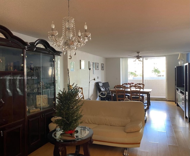 living room featuring ceiling fan with notable chandelier and light hardwood / wood-style flooring