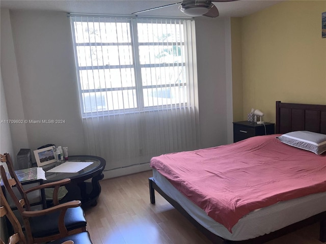 bedroom featuring hardwood / wood-style floors, baseboard heating, and ceiling fan