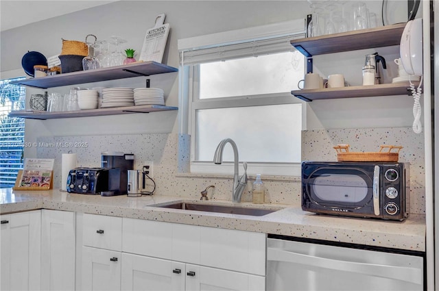 kitchen featuring a wealth of natural light, dishwasher, sink, and white cabinets