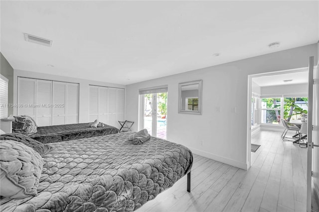 bedroom with access to outside, two closets, and light hardwood / wood-style flooring