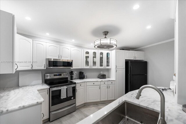 kitchen featuring white cabinetry, stainless steel appliances, light stone counters, crown molding, and light hardwood / wood-style floors