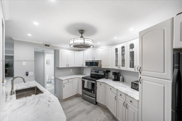 kitchen featuring appliances with stainless steel finishes, light stone counters, white cabinetry, and sink