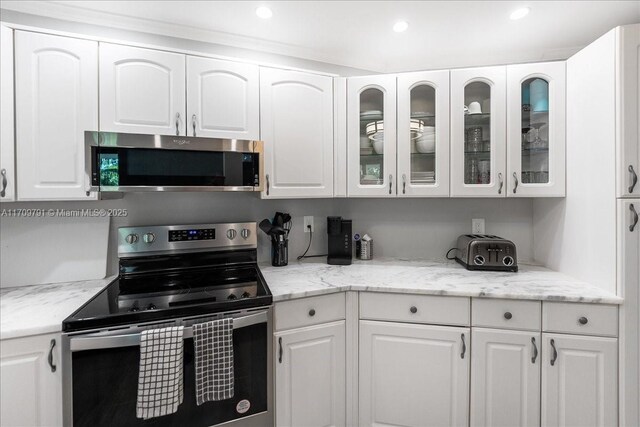 kitchen with white cabinets, appliances with stainless steel finishes, and light stone countertops