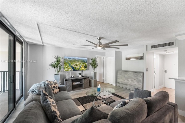 living room with ceiling fan, light hardwood / wood-style floors, and a textured ceiling