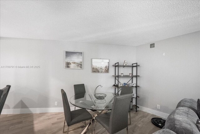 dining space with wood-type flooring and a textured ceiling