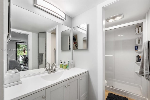 bathroom featuring vanity, wood-type flooring, an enclosed shower, and toilet