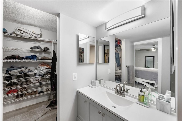 bathroom with a textured ceiling, vanity, and ceiling fan