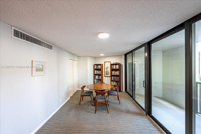 dining space featuring expansive windows, carpet, and a textured ceiling