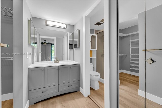 bathroom with ceiling fan, toilet, wood-type flooring, and vanity