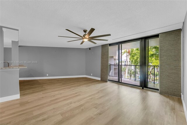 empty room featuring a textured ceiling, light wood-type flooring, and ceiling fan