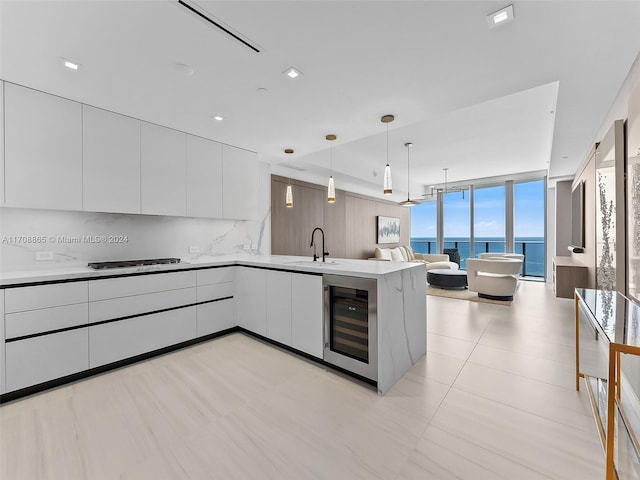 kitchen featuring sink, hanging light fixtures, wine cooler, a water view, and white cabinets