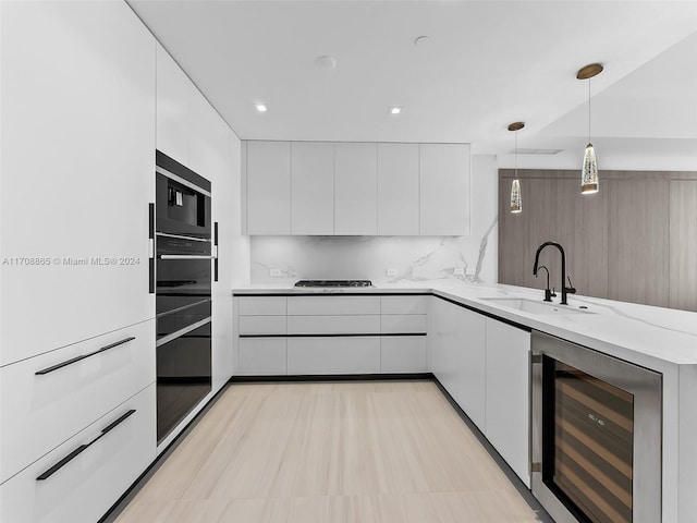 kitchen featuring sink, white cabinets, beverage cooler, and decorative light fixtures