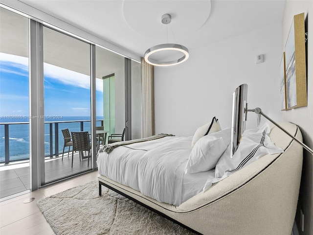 tiled bedroom featuring access to exterior, expansive windows, and a water view