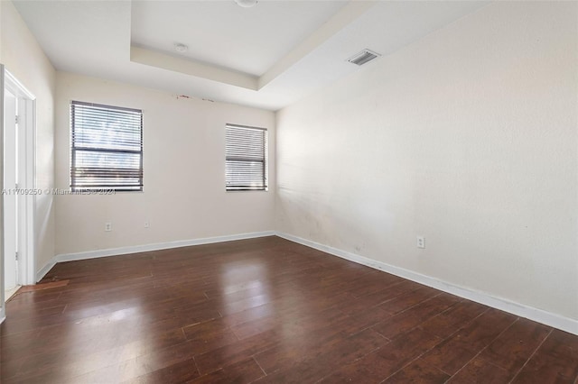 unfurnished room featuring dark hardwood / wood-style floors and a tray ceiling