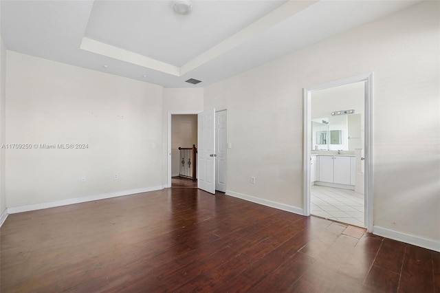 empty room with a raised ceiling and dark hardwood / wood-style flooring