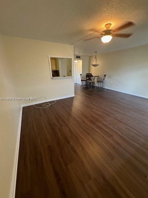 spare room with a textured ceiling, dark hardwood / wood-style flooring, and ceiling fan