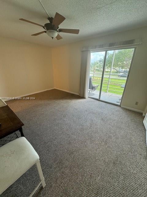 empty room with ceiling fan, carpet, and a textured ceiling