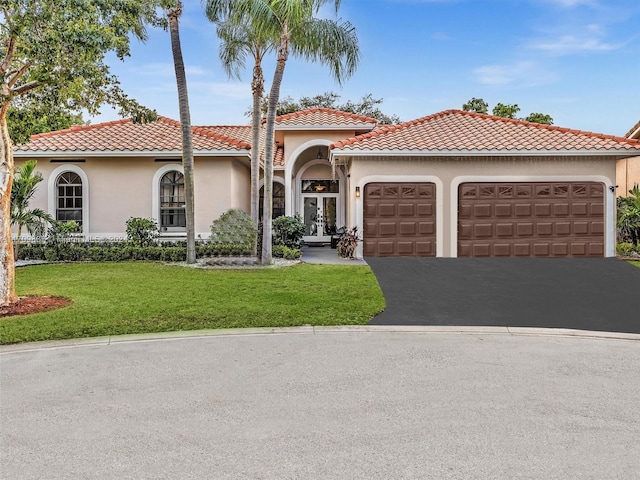 mediterranean / spanish-style home featuring a garage, a front yard, and french doors