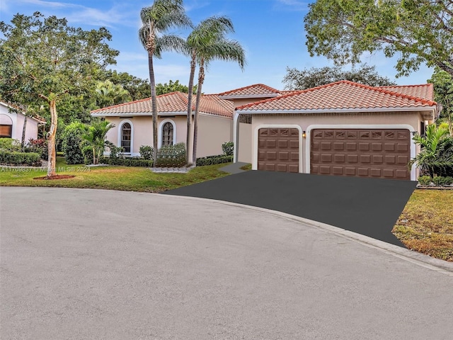 mediterranean / spanish home featuring a front yard and a garage