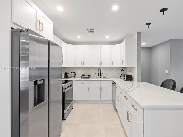 kitchen with white cabinetry, sink, stainless steel appliances, light stone counters, and kitchen peninsula