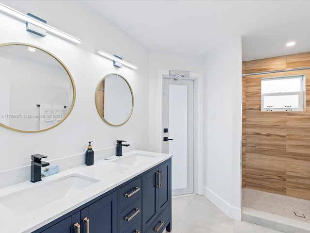 bathroom with a tile shower, vanity, and tile patterned floors