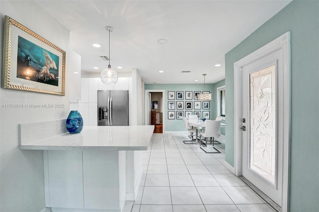 kitchen featuring white cabinetry, a peninsula, light tile patterned floors, stainless steel refrigerator with ice dispenser, and visible vents