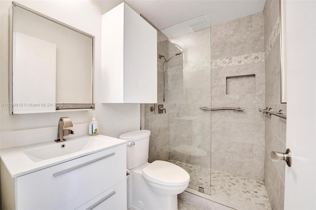 bathroom featuring a tile shower, toilet, and vanity