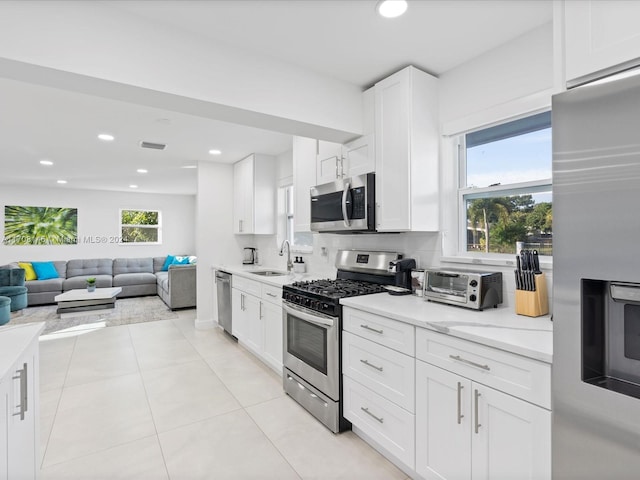 kitchen featuring white cabinets, sink, light tile patterned floors, appliances with stainless steel finishes, and tasteful backsplash