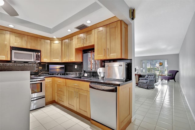 kitchen with light brown cabinetry, backsplash, stainless steel appliances, and sink