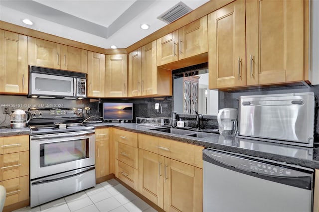 kitchen with decorative backsplash, dark stone counters, stainless steel appliances, sink, and light tile patterned floors