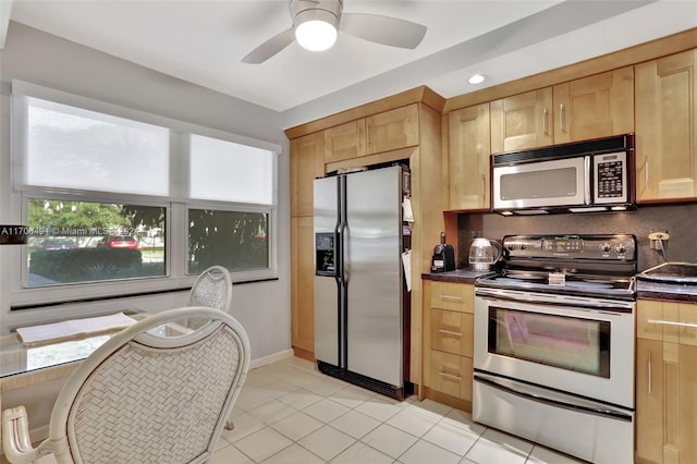 2301 Lucaya Ln Unit M1, Coconut Creek, FL 33066 - kitchen featuring stainless steel appliances, dark countertops, light brown cabinetry, light tile patterned flooring, and a ceiling fan