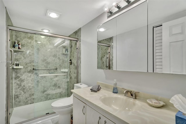 bathroom featuring tile patterned flooring, vanity, toilet, and a shower with shower door