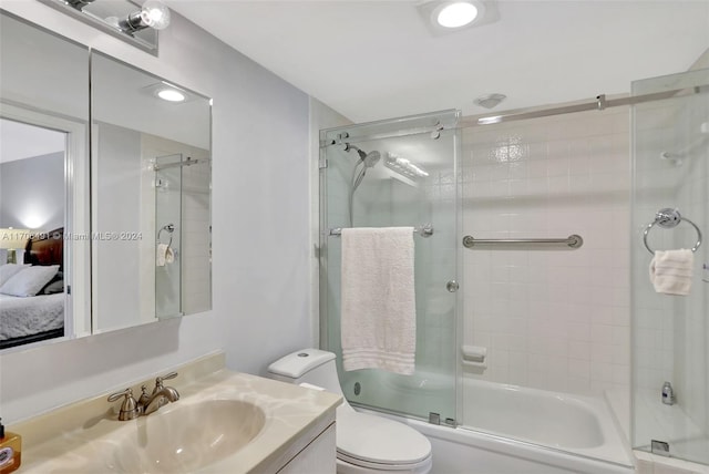 full bathroom with combined bath / shower with glass door, vanity, and toilet