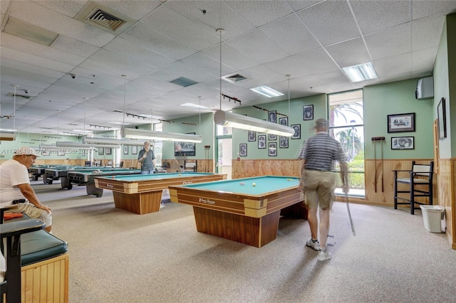 recreation room featuring a drop ceiling, wood walls, light colored carpet, and billiards