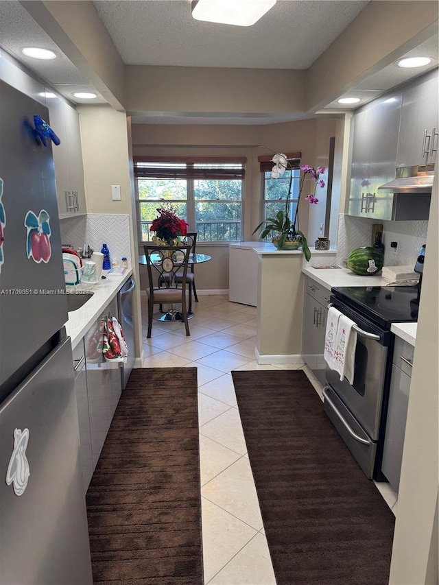 kitchen with appliances with stainless steel finishes, backsplash, a textured ceiling, and light tile patterned floors