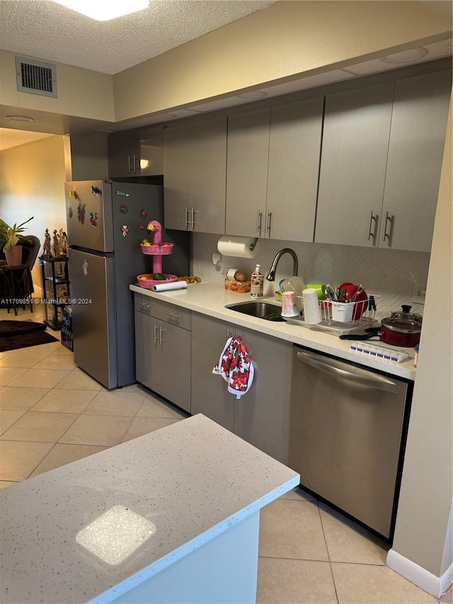 kitchen featuring sink, decorative backsplash, gray cabinets, light tile patterned floors, and stainless steel appliances