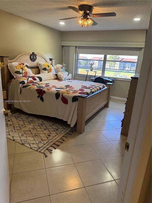 tiled bedroom featuring ceiling fan and a textured ceiling