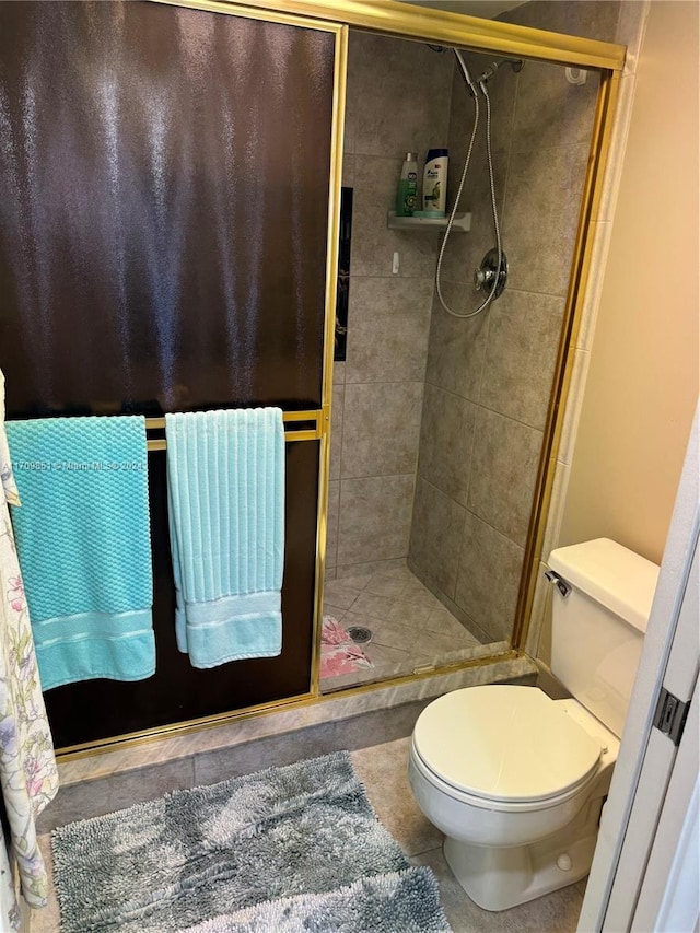 bathroom with tile patterned flooring, toilet, and a tile shower