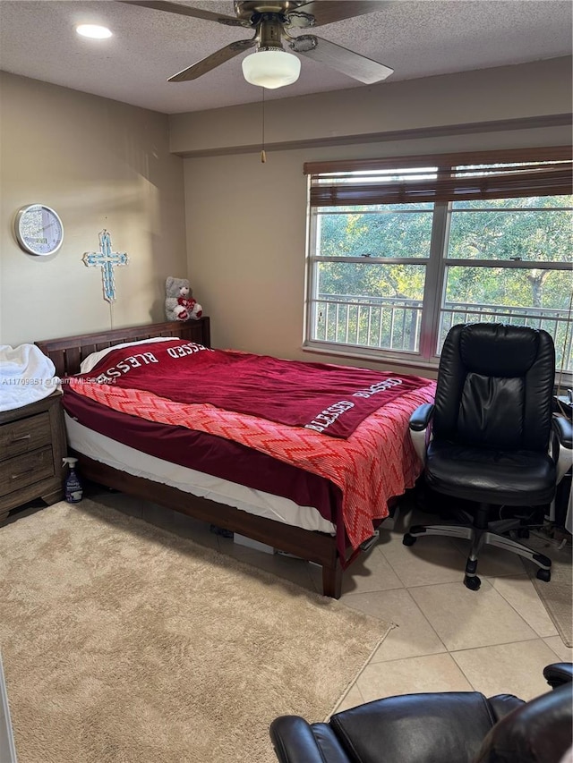 bedroom featuring ceiling fan, light tile patterned floors, and a textured ceiling