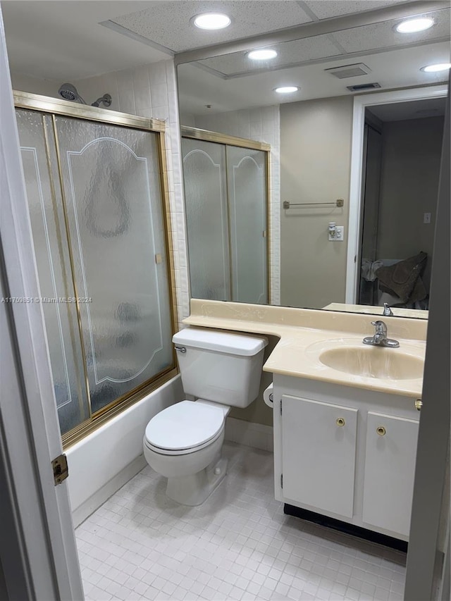 full bathroom with tile patterned floors, vanity, bath / shower combo with glass door, and toilet