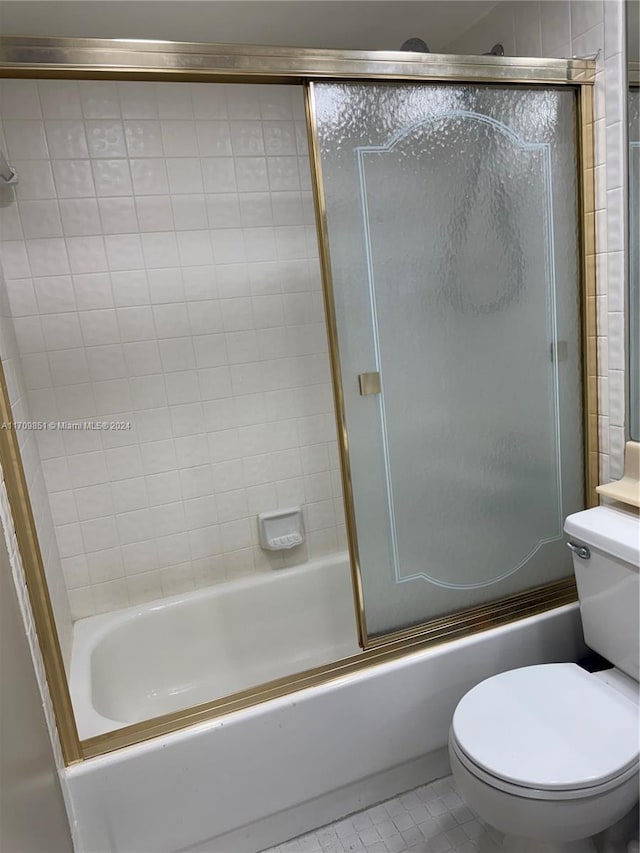 bathroom with tile patterned floors, toilet, and shower / bath combination with glass door