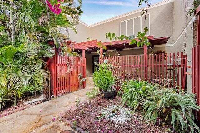 view of front of home featuring a pergola, fence, and stucco siding