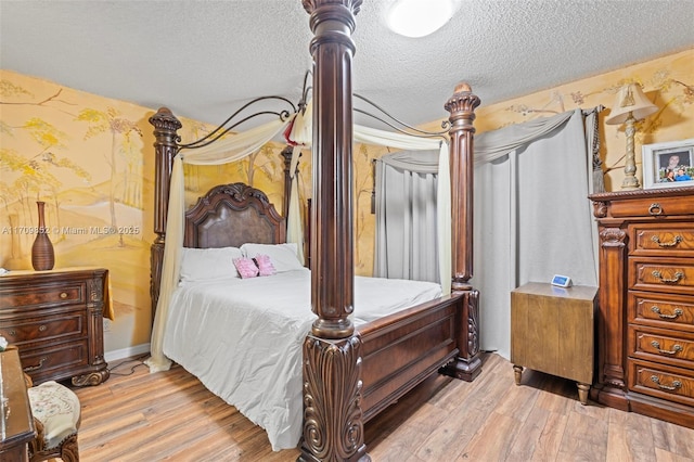 bedroom with light wood-style floors, a textured ceiling, baseboards, and wallpapered walls