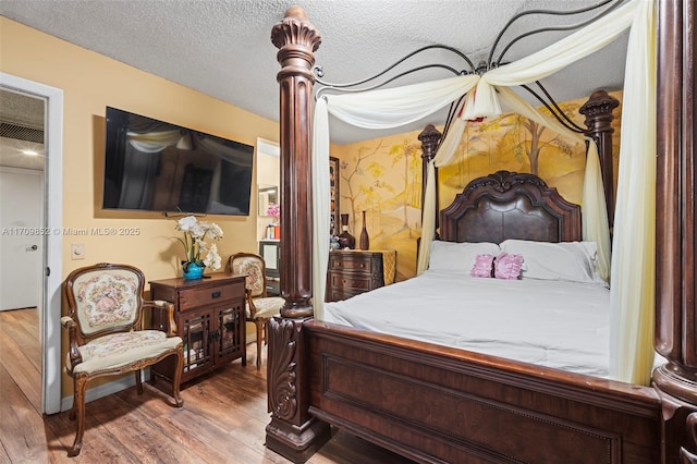 bedroom with a textured ceiling and wood finished floors