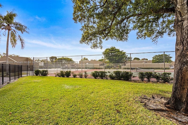 view of yard with a tennis court and fence